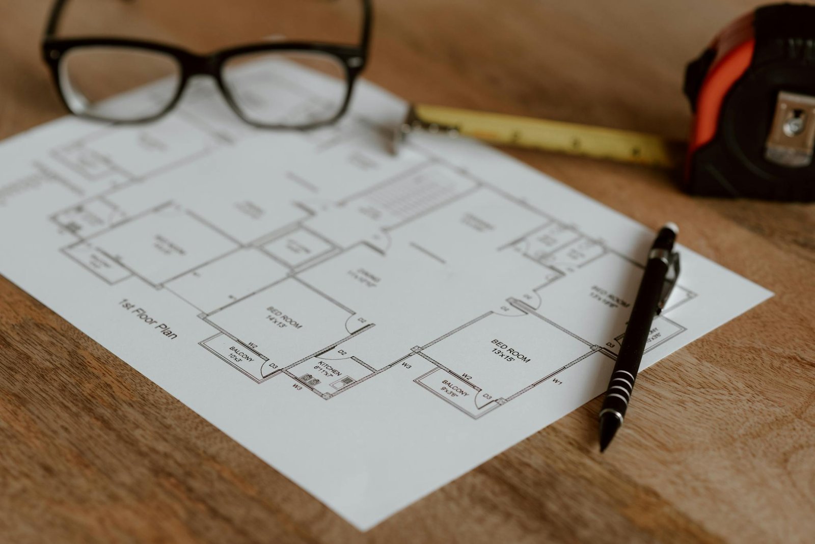 From above of ruler with pencil and glasses placed on paper sheet of house plan for construction